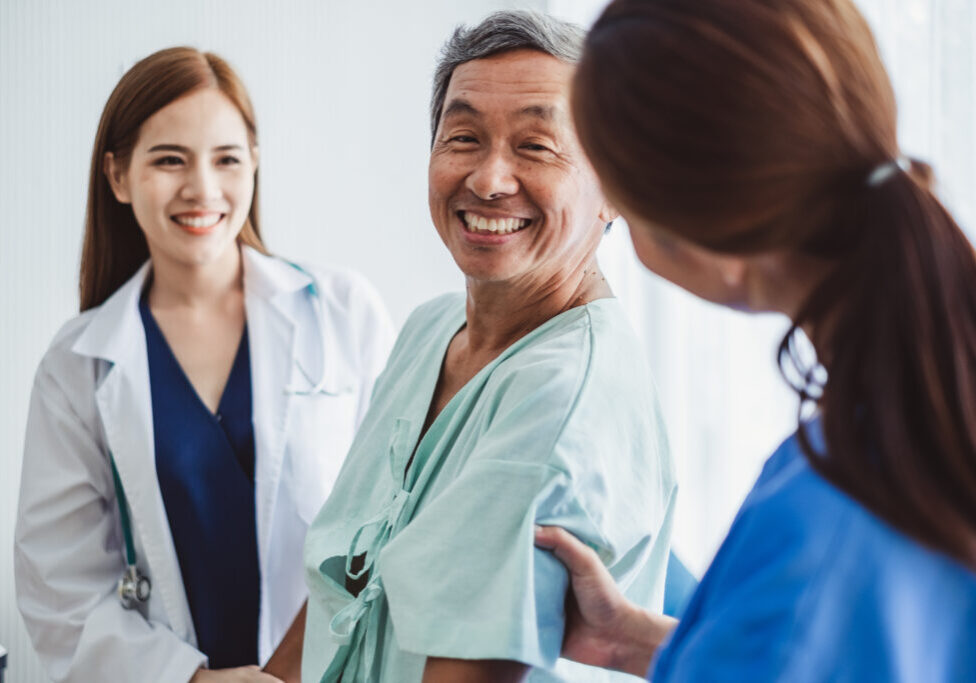 Asian doctor woman and nurse encourage disabled old man patient sitting on wheelchair at hospital, asian medical concept