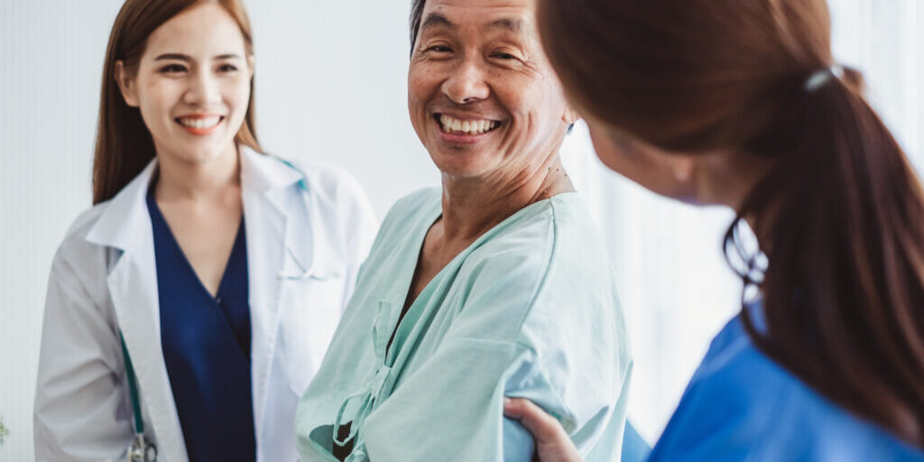 Asian doctor woman and nurse encourage disabled old man patient sitting on wheelchair at hospital, asian medical concept