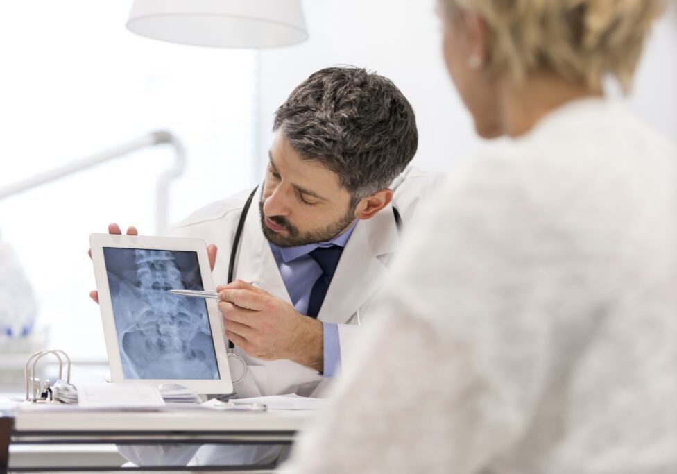 Doctor explaining x-ray on digital tablet to patient at desk in hospital