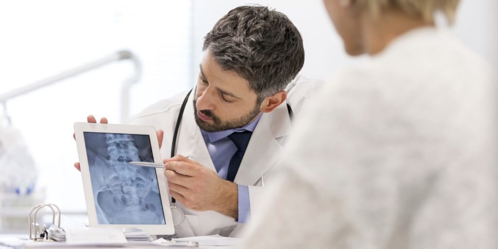 Doctor explaining x-ray on digital tablet to patient at desk in hospital